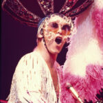 Elton John con vestuario extravagante en un concierto, homenajeado en Rocket Man del Norwegian Luna