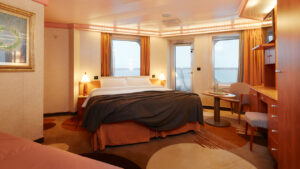 Suite del Costa Serena con cama doble, armarios de madera y luz cálida.