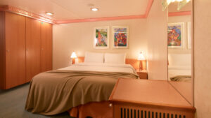 Suite del Costa Serena con cama doble, armarios de madera y luz cálida.