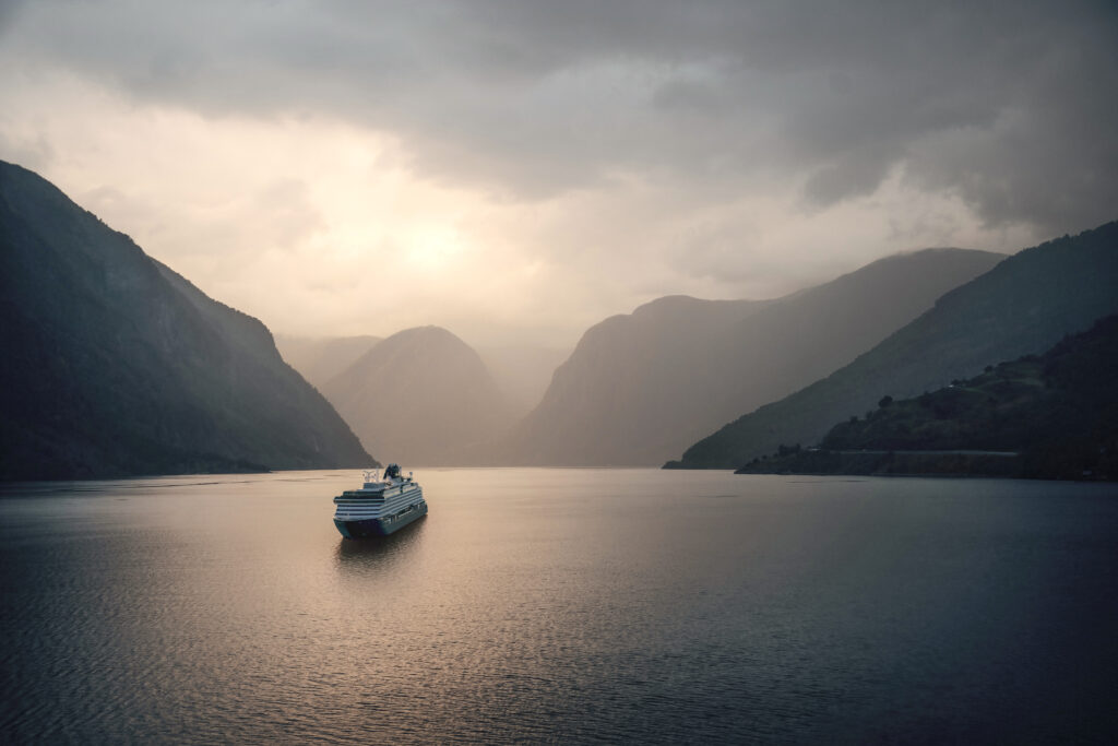Crucero navegando por un fiordo al atardecer, imagen evocadora de viajes oceánicos.
