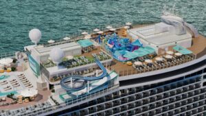 Vista aérea del parque acuático en cubierta: tobogán, zona splash infantil, hamacas y sombrillas junto al mar
