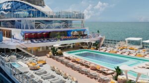 Render del Pool Deck: piscina principal rectangular con solárium, tumbonas, camas redondas y bar exterior en varias alturas