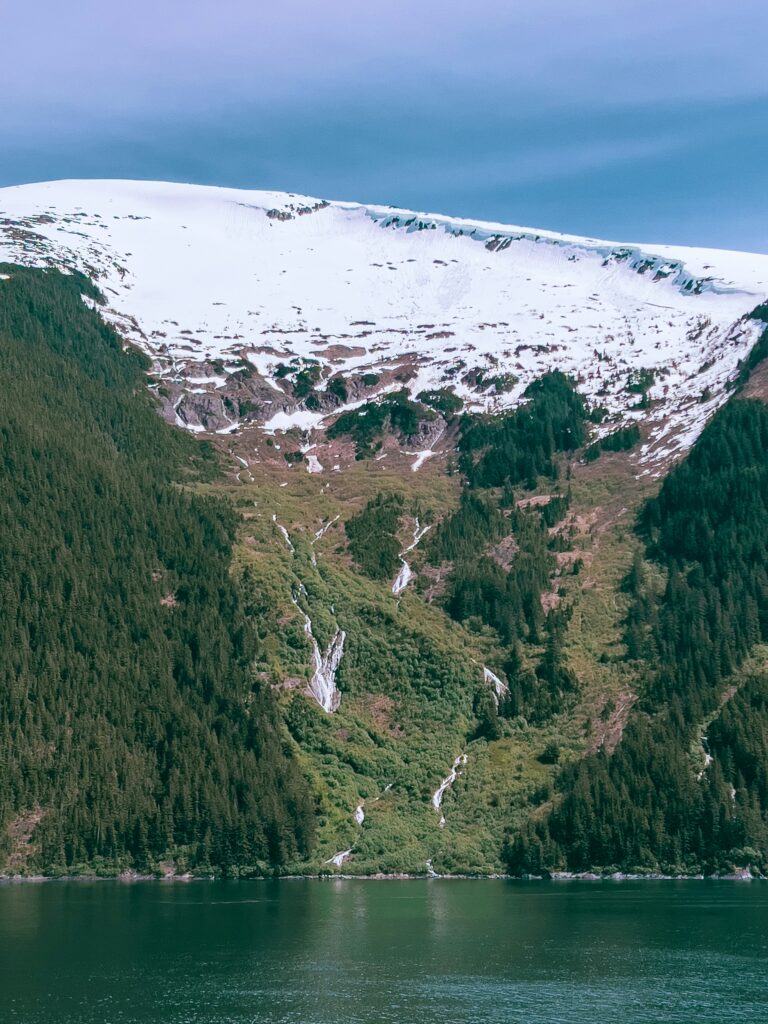 Una montaña llena de nieve junto a un cuerpo de agua