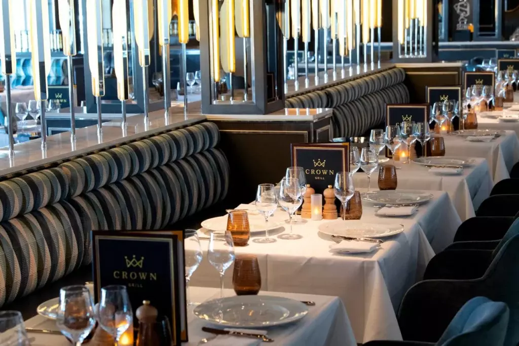 Vista del elegante comedor del restaurante Crown Grill en un buque de Princess Cruises con mesas montadas para una cena gourmet.
