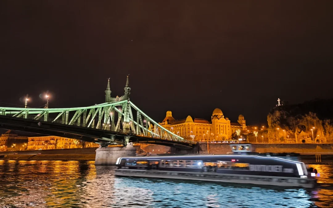 Imagen de un crucero fluvial pasando de noche bajo el Puente de las Cadenas en Budapest.