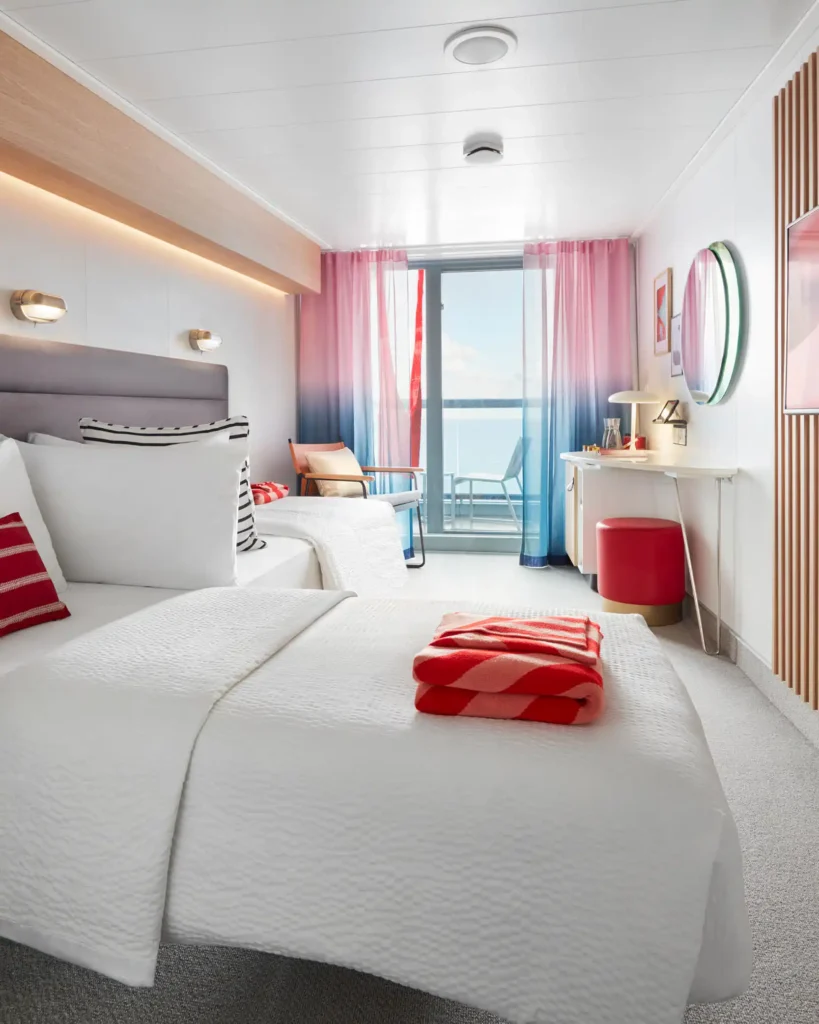 Interior de un camarote Sea Terrace de Virgin Voyages con dos camas separadas, balcón al mar y detalles de diseño vibrantes