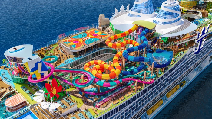 ista aérea detallada de las cubiertas superiores del Hero of the Seas, mostrando los coloridos toboganes del parque acuático Category 6, la cancha polideportiva y las piscinas.