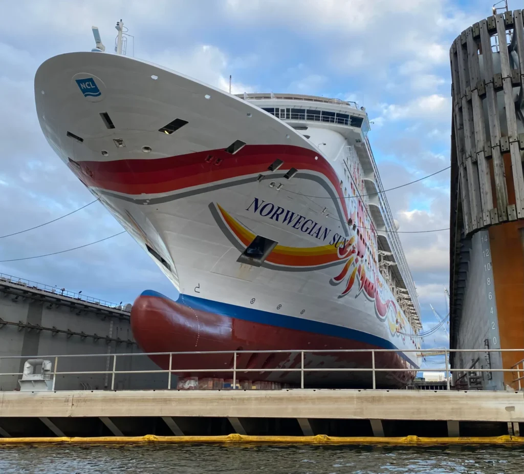 Primer plano de la proa y el bulbo del crucero Norwegian Sun en un dique seco, mostrando el característico arte en su casco.