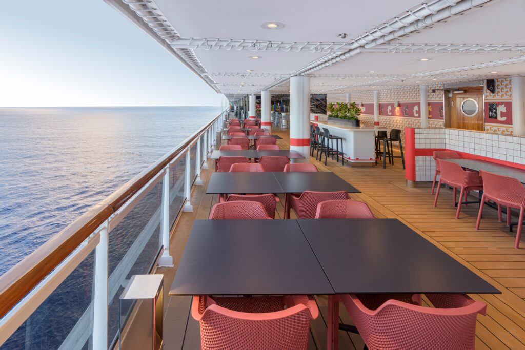 mesas exteriores junto a la barandilla con vistas al oceano en msc seashore