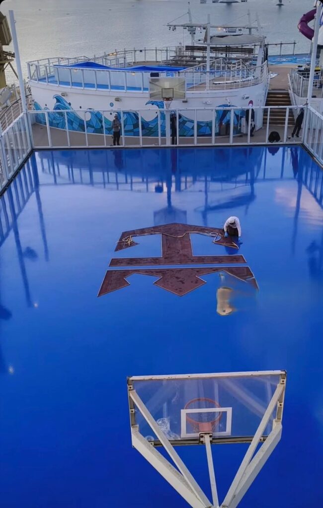 operario pintando el logotipo de royal caribbean en la pista exterior