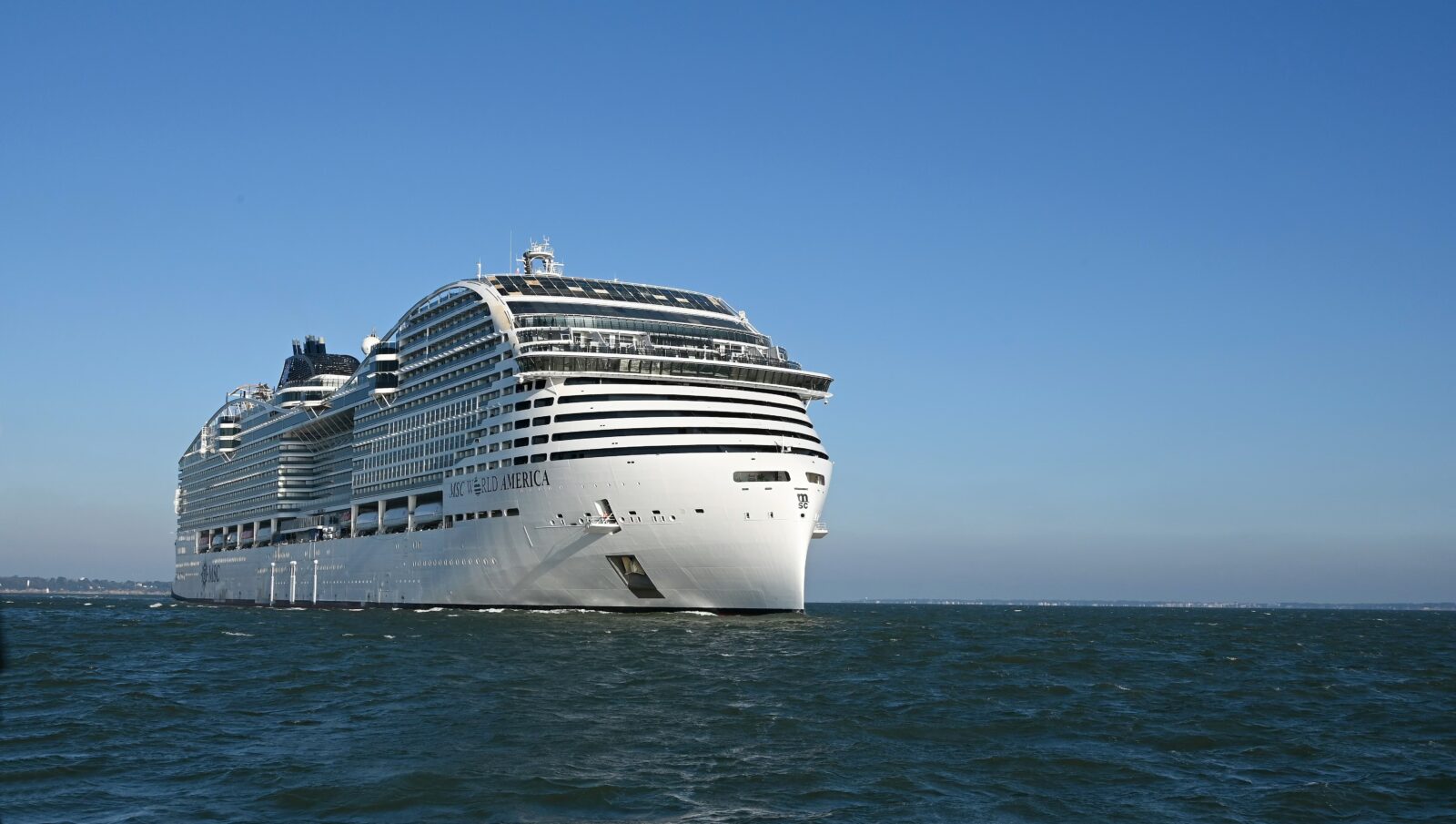El crucero MSC World America navegando sobre el mar en un día soleado con cielo despejado.