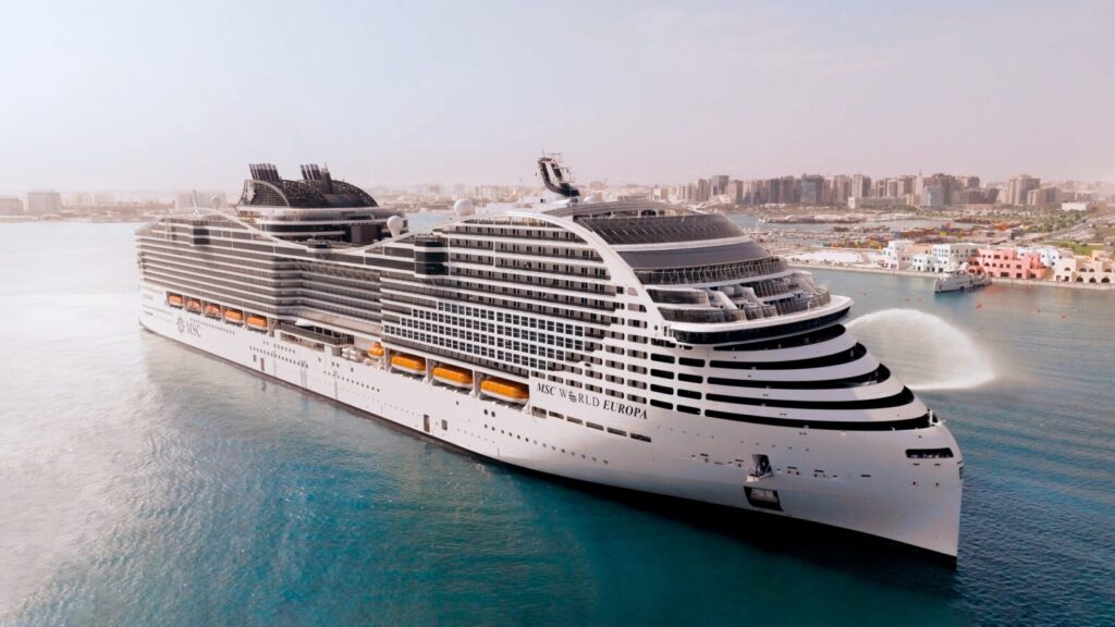 El crucero MSC World Europa navegando cerca de la costa de Doha, Qatar, con un cielo despejado y aguas tranquilas.