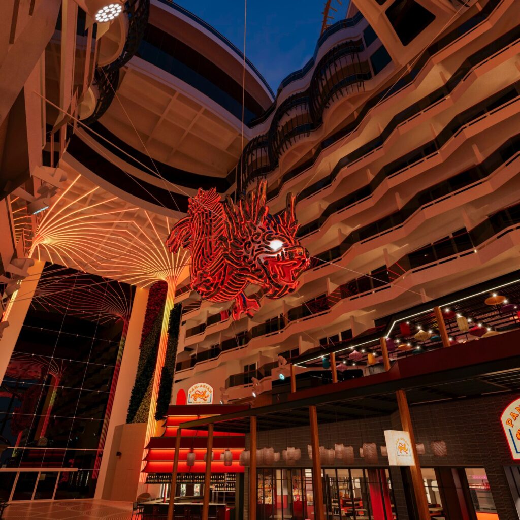 Escultura de dragón roja iluminada suspendida en el atrio central del crucero MSC World Europa sobre bares temáticos.