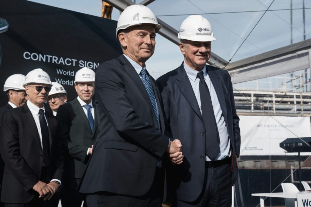 Pierfrancesco Vago y ejecutivos estrechando la mano con cascos de seguridad durante un evento de MSC Cruceros.