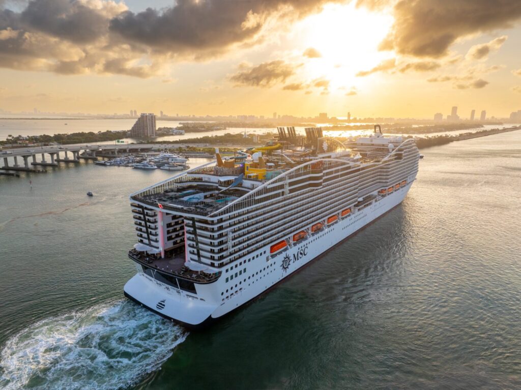 El crucero MSC World America navegando cerca de la costa de Miami durante un atardecer dorado.