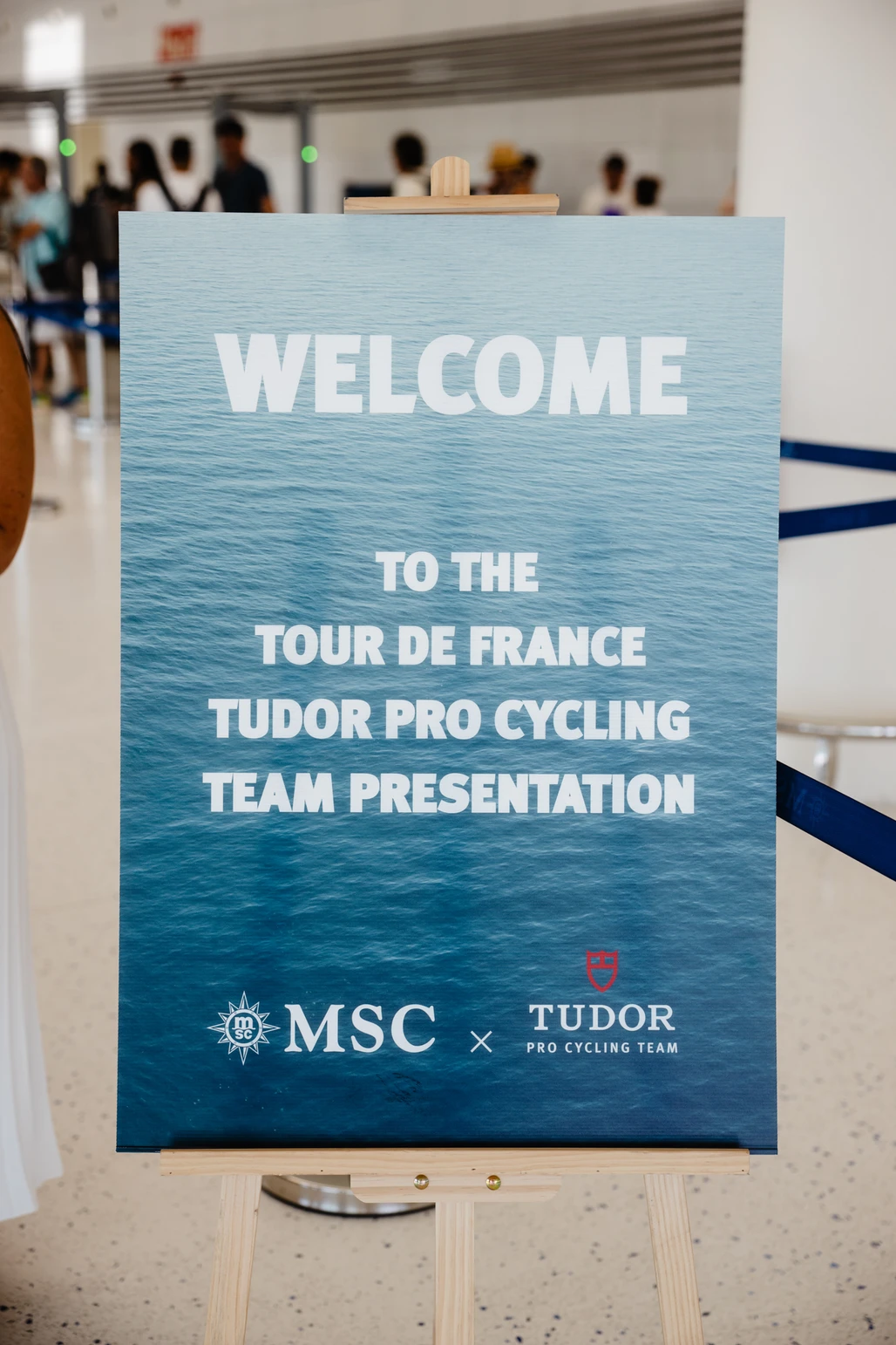 Cartel sobre caballete dando la bienvenida a la presentación del Tudor Pro Cycling Team para el Tour de Francia con MSC.