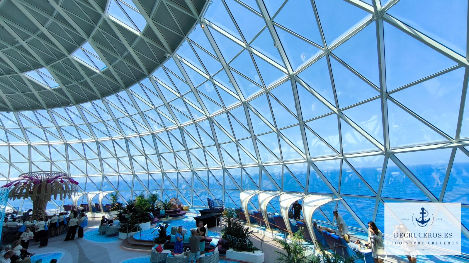 Vista interior del domo AquaDome en un crucero Royal Caribbean con vistas al mar y pasajeros descansando.