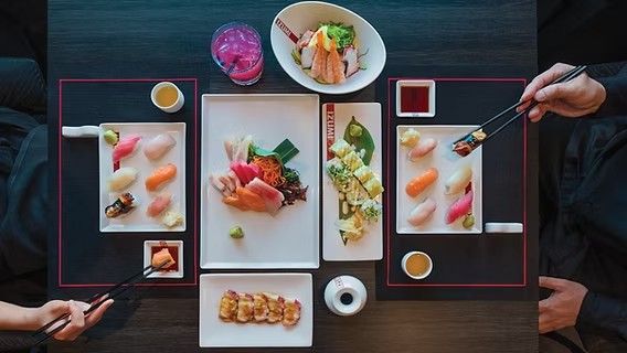 Vista cenital de platos de sushi, sashimi y rollos servidos en el restaurante Izumi a bordo de un crucero.
