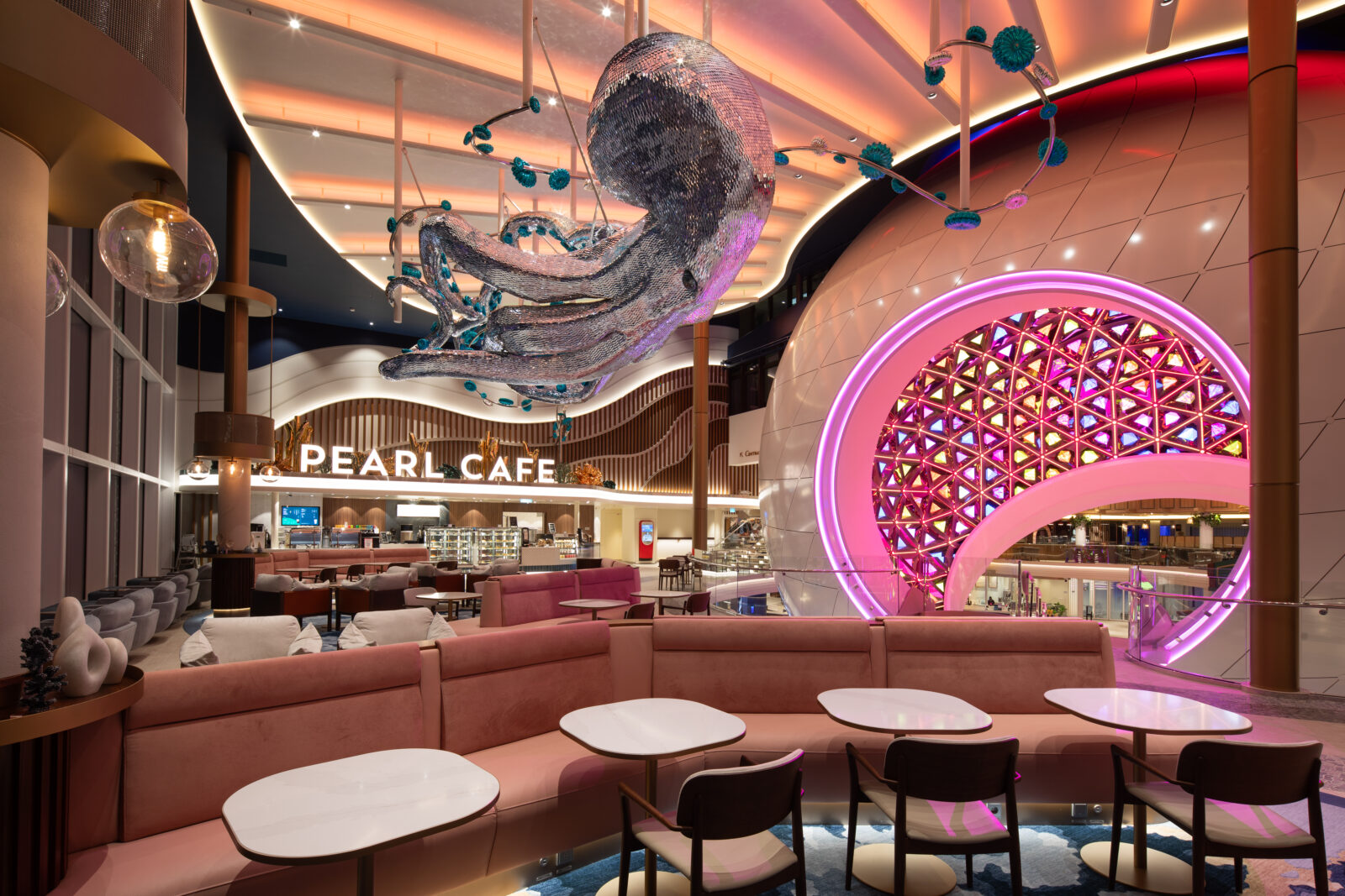 Interior del Pearl Cafe con un pulpo decorativo plateado que cuelga del techo y sofás de color rosa.