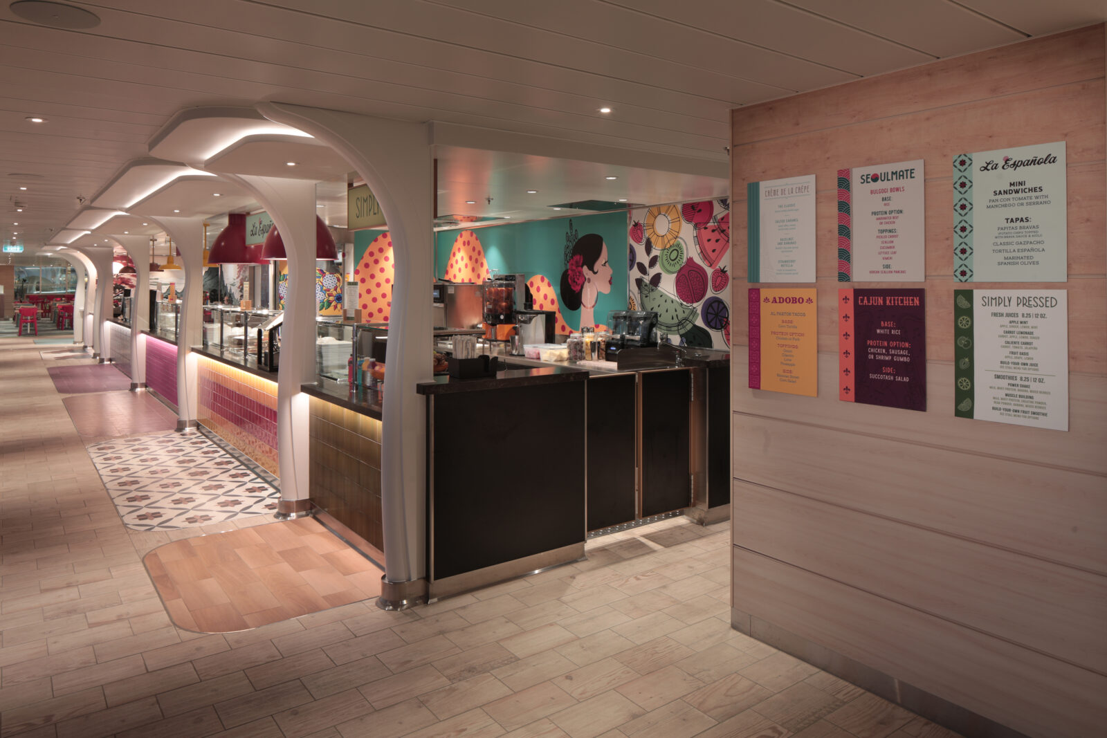 Pasillo de un mercado gastronómico con puestos de comida internacional, murales artísticos y menús en la pared