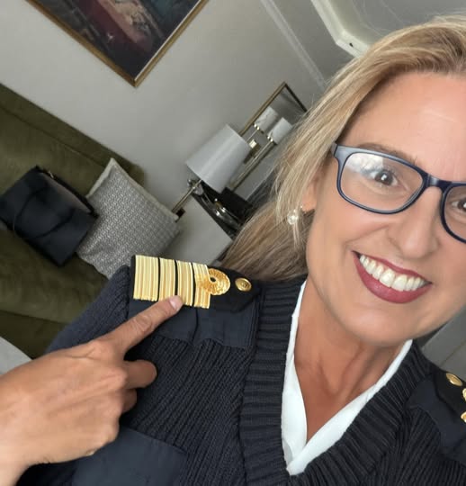 María Gotor sonriendo mientras señala las insignias doradas en el hombro de su uniforme de oficial de crucero.