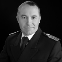 Retrato en blanco y negro de un capitán de crucero con uniforme formal y galones en los hombros.