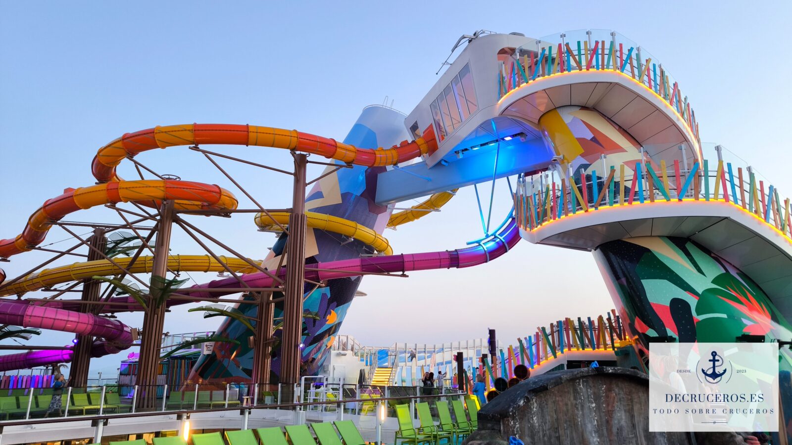 Toboganes acuáticos de colores brillantes y plataforma elevada en la cubierta superior de un crucero Royal Caribbean.